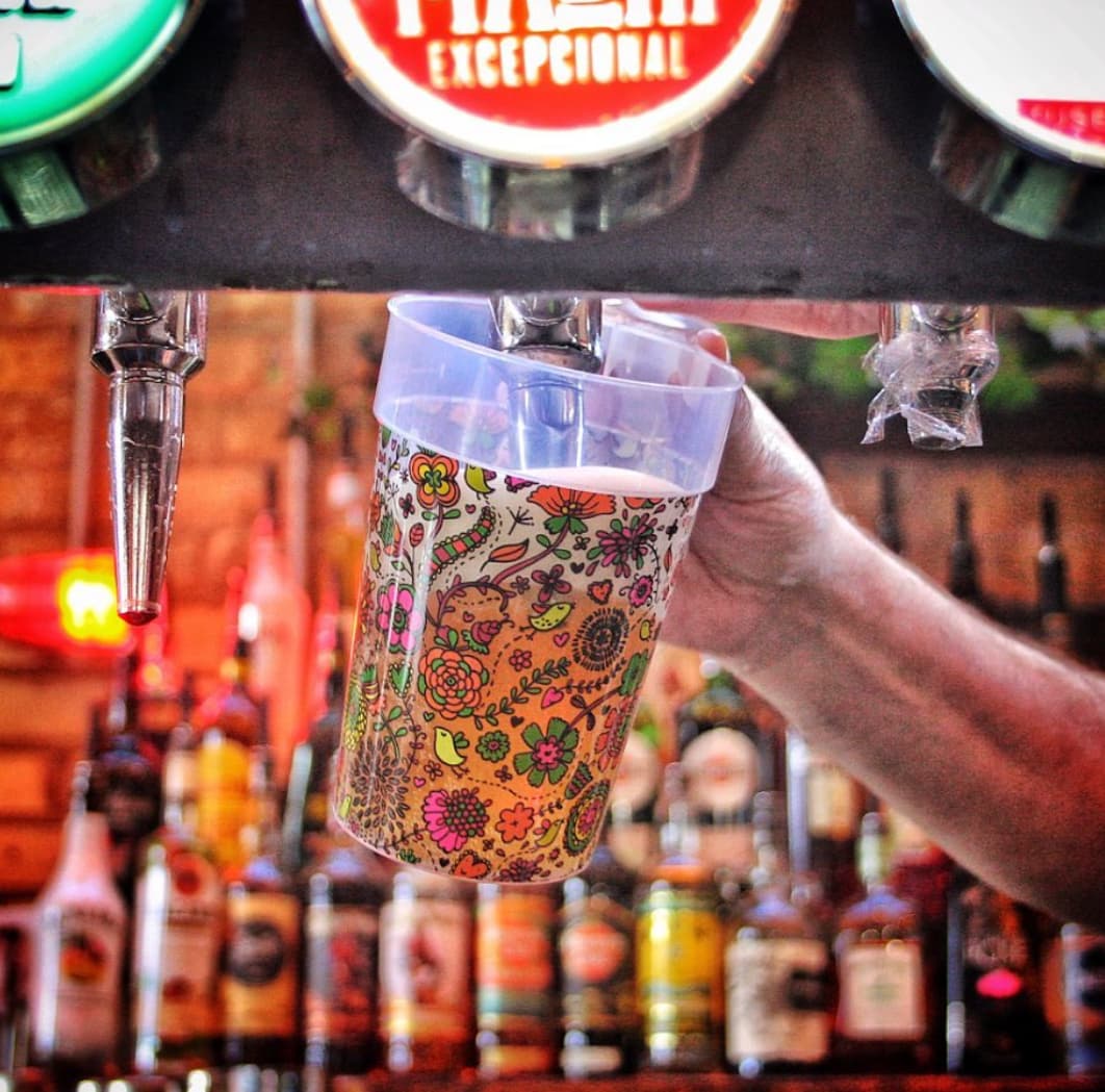 A row of vibrant, custom-printed reusable festival cups manufactured by Drinksmate in the UK
